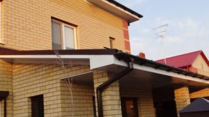 Водосточная система Дёке Люкс шоколад на доме из жёлтого кирпича